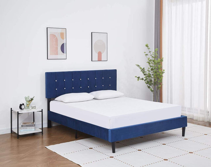 a white mattress and pillows on a royal blue velvet upholstered bed base that comes with a headboard decorated with faux diamond buttons 